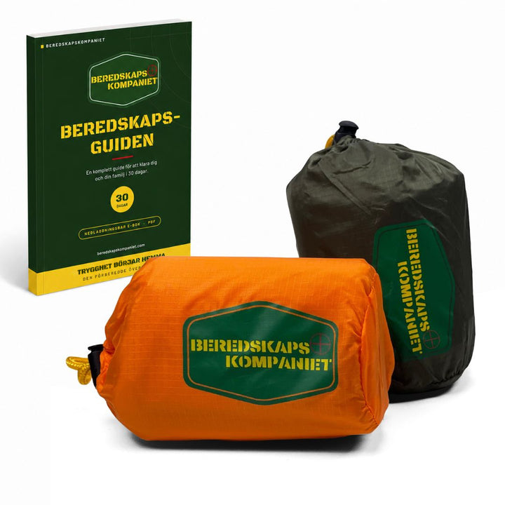 Orange och grön bivy bag nödsovsäck i packpåse bredvid Beredskapsguiden
